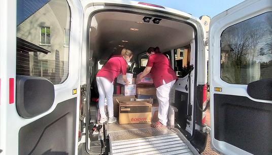 Spendenaktion für geflüchtete ukrainische Kinder | Mitarbeitende packen Kisten in den Transporter